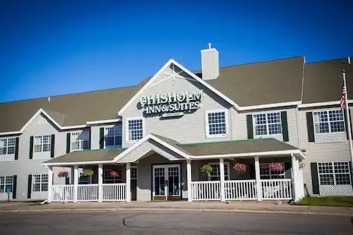 The front of Chisholm Inn & Suites, with the property sign above the entrance