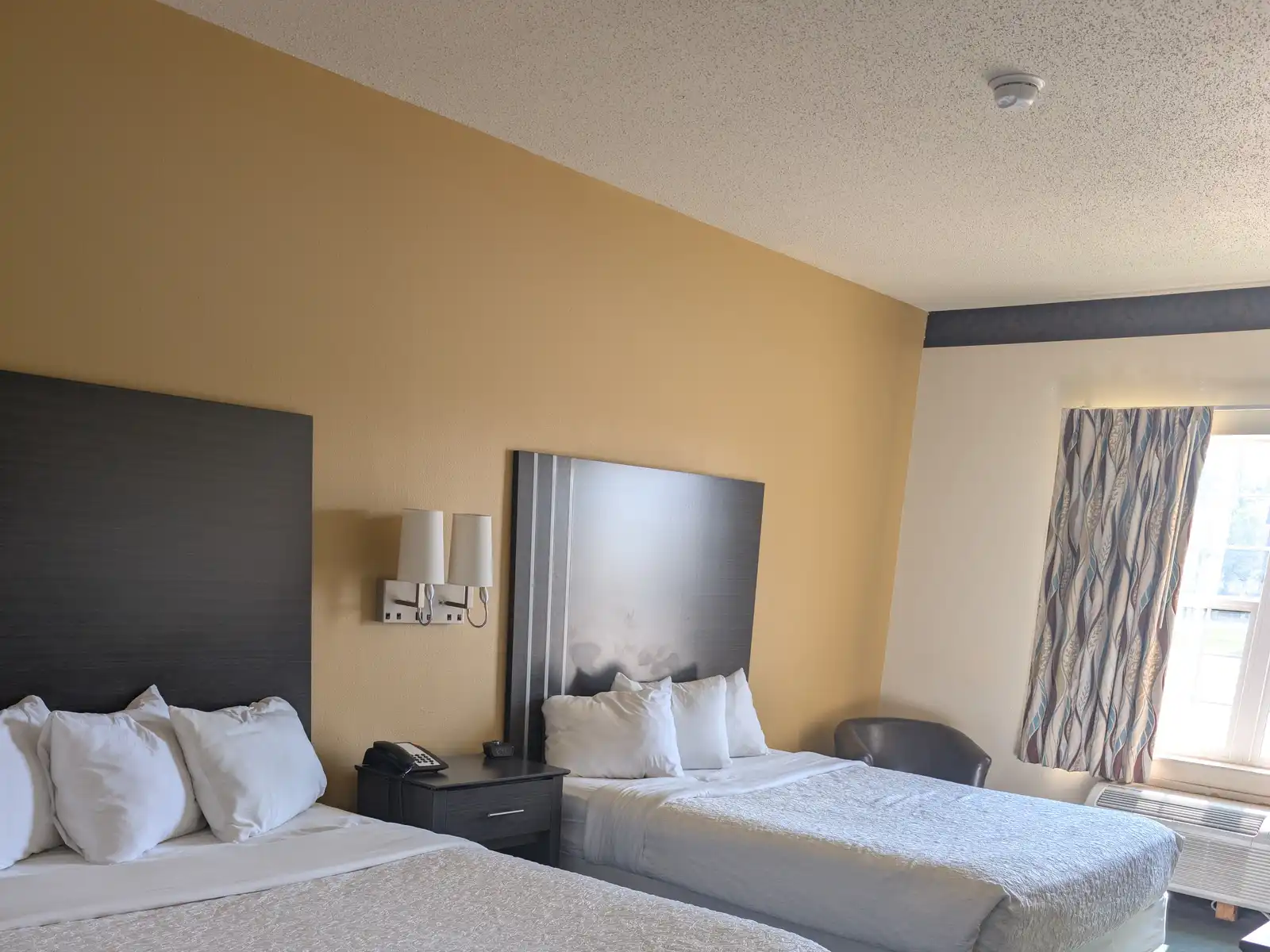 A Double Queen room at Chisholm Inn & Suites with two queen beds
